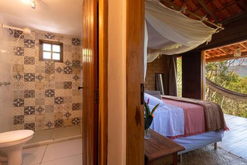 a bedroom with a bed and a bathroom with a window at Lilás Hospedagem e Terapias in Vale do Capao