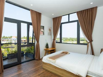 a bedroom with a large bed and large windows at Alina Retreat in Hiếu Nhơn