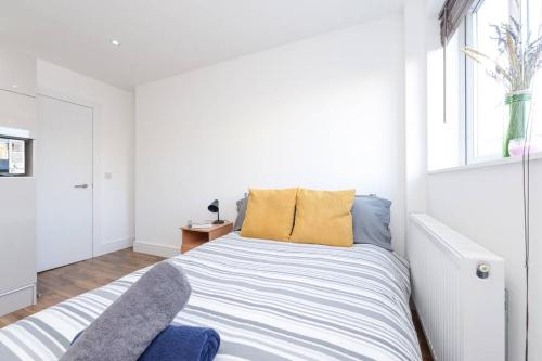a white bedroom with a bed and a window at City Sparrow Apartments 12 in London