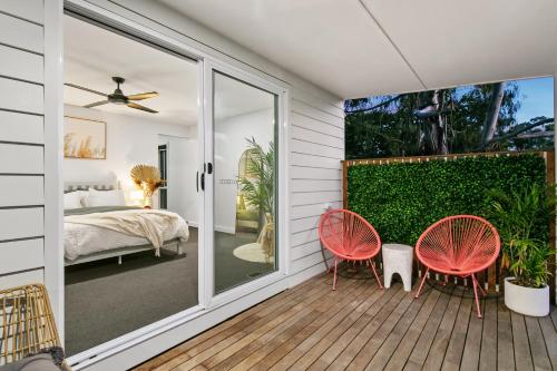 a bedroom with a bed and two chairs on a deck at Getaway On Little in Daylesford