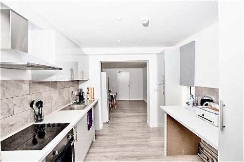 a kitchen with white counters and a long hallway at Dunamis Staycation 2 in Croydon