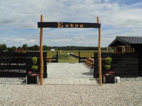 a sign for an entrance with potted plants and a field at Vestbjerg Apartments in Vestbjerg