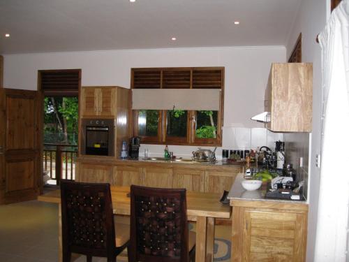 a kitchen with wooden cabinets and a table and chairs at Casa Verde in Grand'Anse Praslin