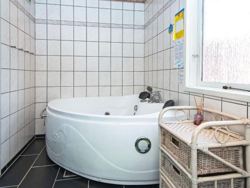 a white tub in a white tiled bathroom with a window at 6 person holiday home in Hemmet in Falen