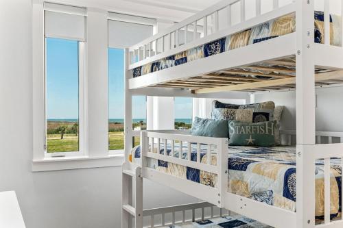 Una litera blanca en una habitación blanca con ventana. en Paradise By The Sea home, en Bolivar Peninsula