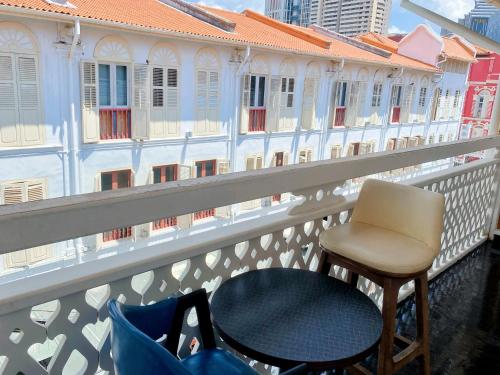 a chair and a table on a balcony with buildings at Hotel Calmo Chinatown in Singapore