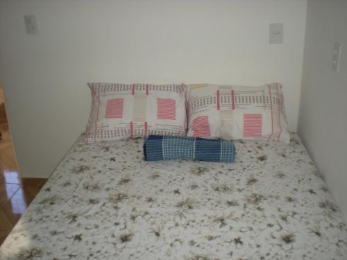 a bed with three pillows on top of it at Hostel Morais in Maceió