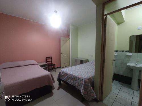 a bedroom with a bed and a bathroom with a sink at Rooms MD in Huancayo