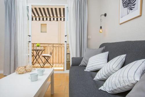 uma sala de estar com um sofá cinzento com almofadas em Cosy 3-bedroom apartment for 6-8 people just 50m from the beach em Salou