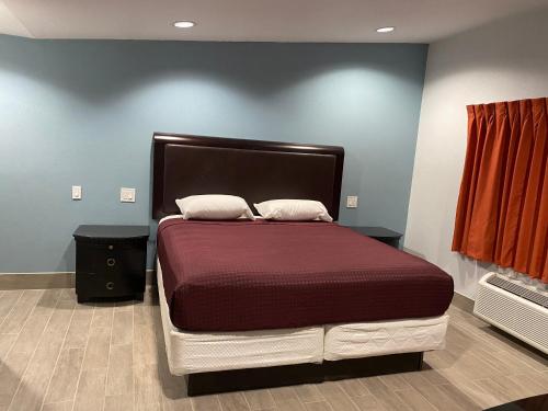 uma cama grande num quarto com uma parede vermelha em Executive Inn em Hobbs
