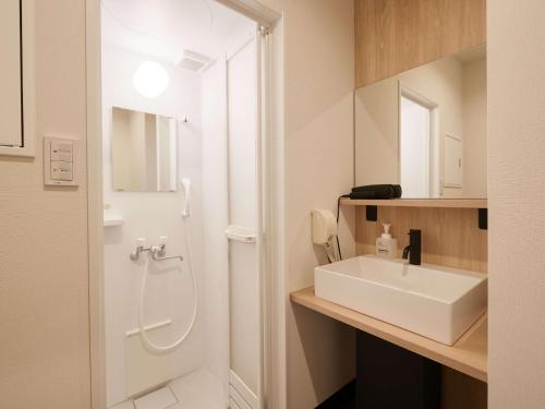 a white bathroom with a sink and a mirror at CABIN&HOTEL CONSTANT NAHA in Naha