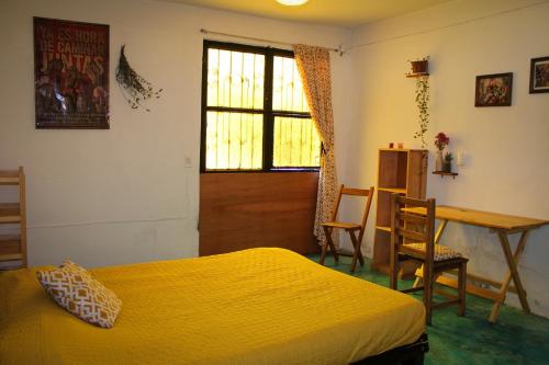 a bedroom with a bed and a desk and a window at Casa Huipil in San Cristóbal de Las Casas
