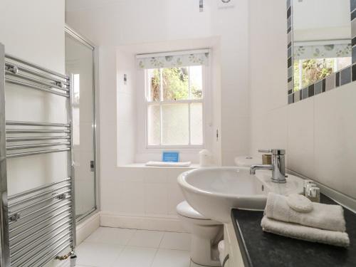 a white bathroom with a sink and a shower at Glen Cottage in Penrith