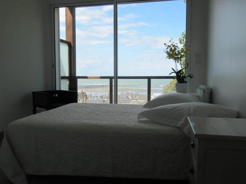 a bedroom with a bed and a large window at Villa Régina in Trouville-sur-Mer