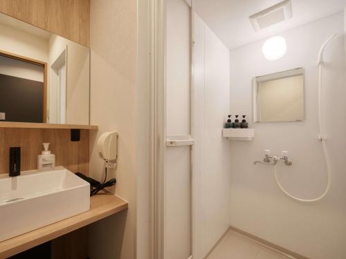 a white bathroom with a sink and a shower at CABIN&HOTEL CONSTANT NAHA in Naha