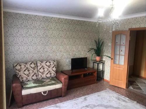 a living room with a couch and a television at Апартаменты на Утепбаева 1 in Semey
