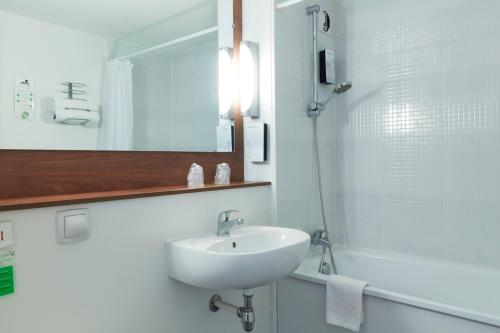 La salle de bains blanche est pourvue d'un lavabo et d'une douche. dans l'établissement Campanile Lille - Lomme, à Lomme