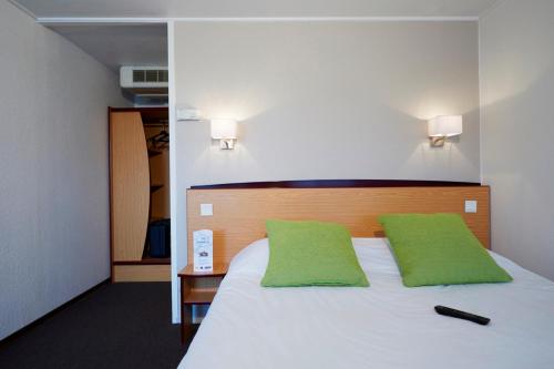 a bedroom with a white bed with green pillows at Campanile Lille - Lomme in Lomme