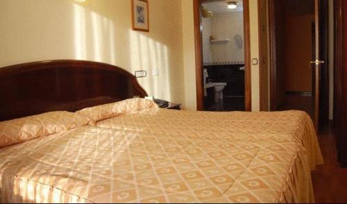 a bedroom with a bed with a wooden head board at Hotel Piedra in Perlora