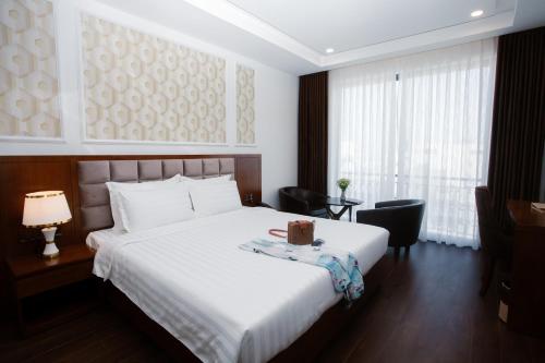 - une chambre avec un lit blanc et une fenêtre dans l'établissement Century Hotel Da Nang, à Đà Nẵng