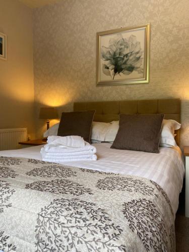 a bedroom with a large bed with white sheets and pillows at Melbourne Guest House in Bowness-on-Windermere