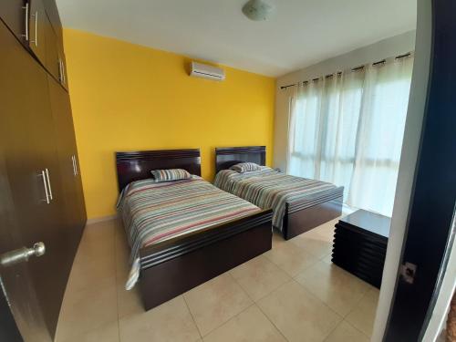 two beds in a room with yellow walls at Apartamento en Playa Blanca - PANAMÁ in Río Hato