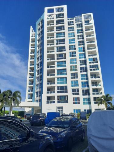 a large building with cars parked in a parking lot at Apartamento en Playa Blanca - PANAMÁ in Río Hato