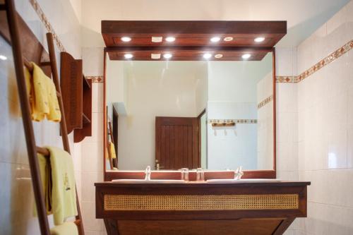 a bathroom with a sink and a large mirror at Vanila Hotel & Spa in Ambaro