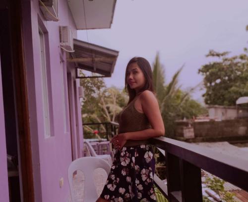 a young girl is standing on a balcony at Purple Guesthouse in Nasugbu