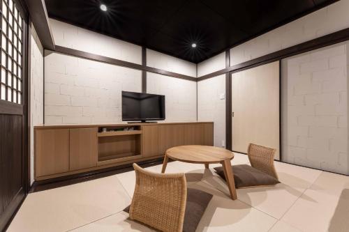 a room with a tv and a table and chairs at Yufudake Ichibo no Yado Kirara in Yufuin