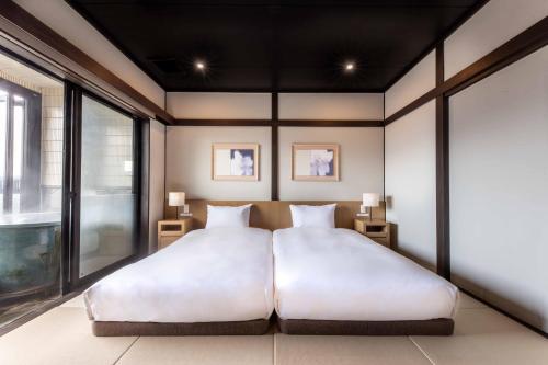 a bedroom with a large white bed and a window at Yufudake Ichibo no Yado Kirara in Yufuin