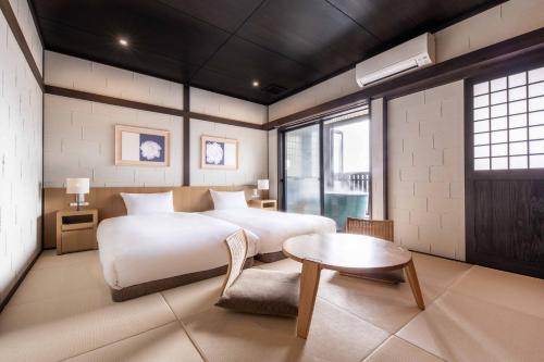 um quarto com uma cama grande e uma mesa em Yufudake Ichibo no Yado Kirara em Yufu