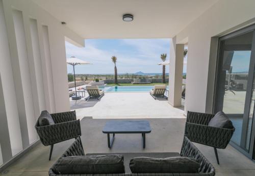 a patio with chairs and a table and a pool at Grand Sea View Luxury Villa in Kalamaki Heraklion