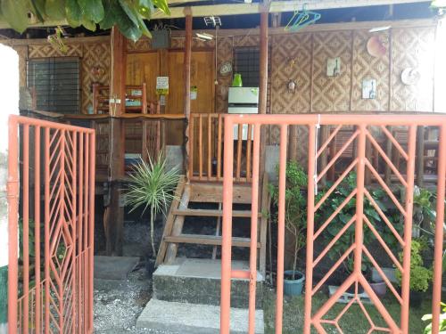 a house with a staircase in front of a fence at Titanic's Nipa Hut in Moalboal