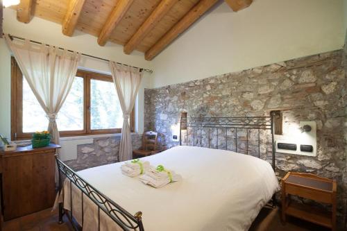 1 dormitorio con 1 cama grande y pared de piedra en Agriturismo BioBiò, en Vobarno