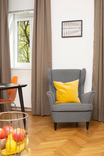 a blue chair with a yellow pillow and a bowl of fruit at Luxury Suites Liechtenstein in Vienna