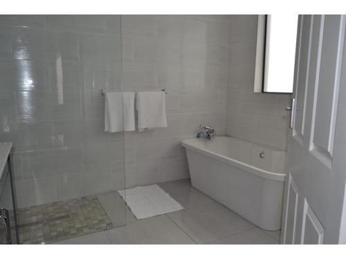 baño blanco con bañera y lavamanos en Furaha Guest Lodge en Johannesburgo