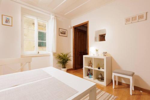 biała sypialnia z łóżkiem i krzesłem w obiekcie Liston Sweet House w Korfu