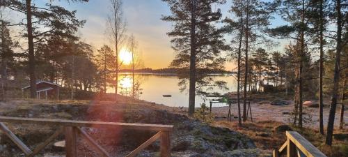 a sunset over a lake with a wooden bench at Rolfskärrs Stugby in Nygård