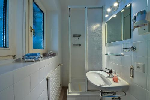 La salle de bains blanche est pourvue d'un lavabo et d'une douche. dans l'établissement Casa Liliane, à Ascona