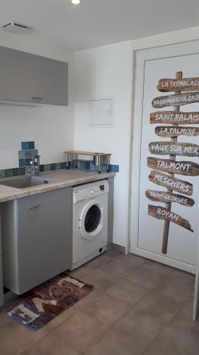 une cuisine avec un lave-linge à côté d'une porte dans l'établissement Étaules 10 min de la palmyre, à Étaules
