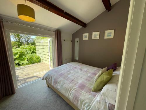 ein Schlafzimmer mit einem Bett und einem großen Fenster in der Unterkunft Beech Hut - a streamside family escape near Salcombe and Beaches in South Milton