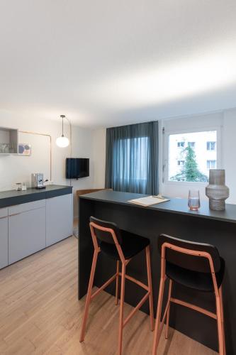 a kitchen with two chairs at a black counter at Alpenblick Bern - kind of a hotel in Bern