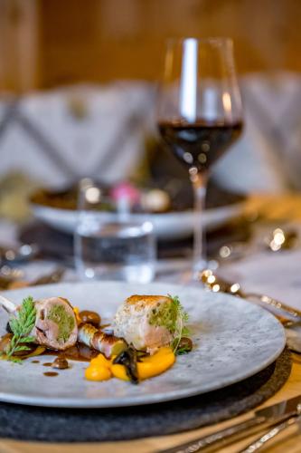 a plate of food on a table with a glass of wine at Naturhotel Alpenblick in Maurach