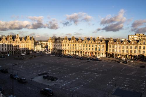 un grand parking en face d'un grand bâtiment dans l'établissement Grand Place Hôtel "Boutique et Appart'hôtel", à Arras