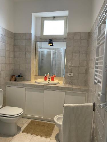 Un baño con lavabo, inodoro y espejo. en Casa Cafè, en Taormina