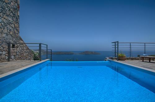 a blue swimming pool with a view of the ocean at Elounda Solfez Villas in Elounda