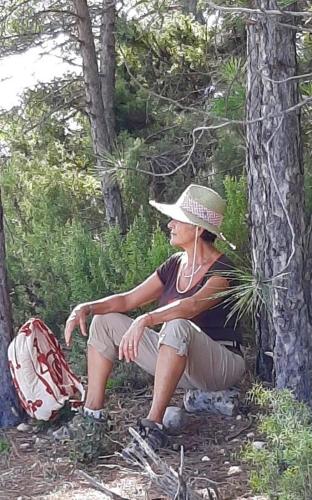 a woman wearing a hat sitting next to a tree at Apartamentos Can Juver in Beceite