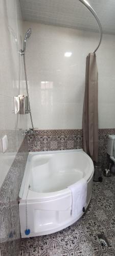 e bagno con vasca bianca e doccia. di Old Street Guesthouse a Bukhara