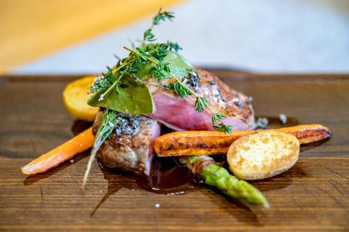 a piece of meat with carrots and other vegetables on a table at Naturhotel Alpenblick in Maurach